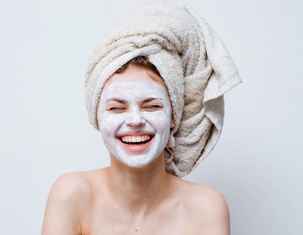 Woman with facial skincare mask laughing